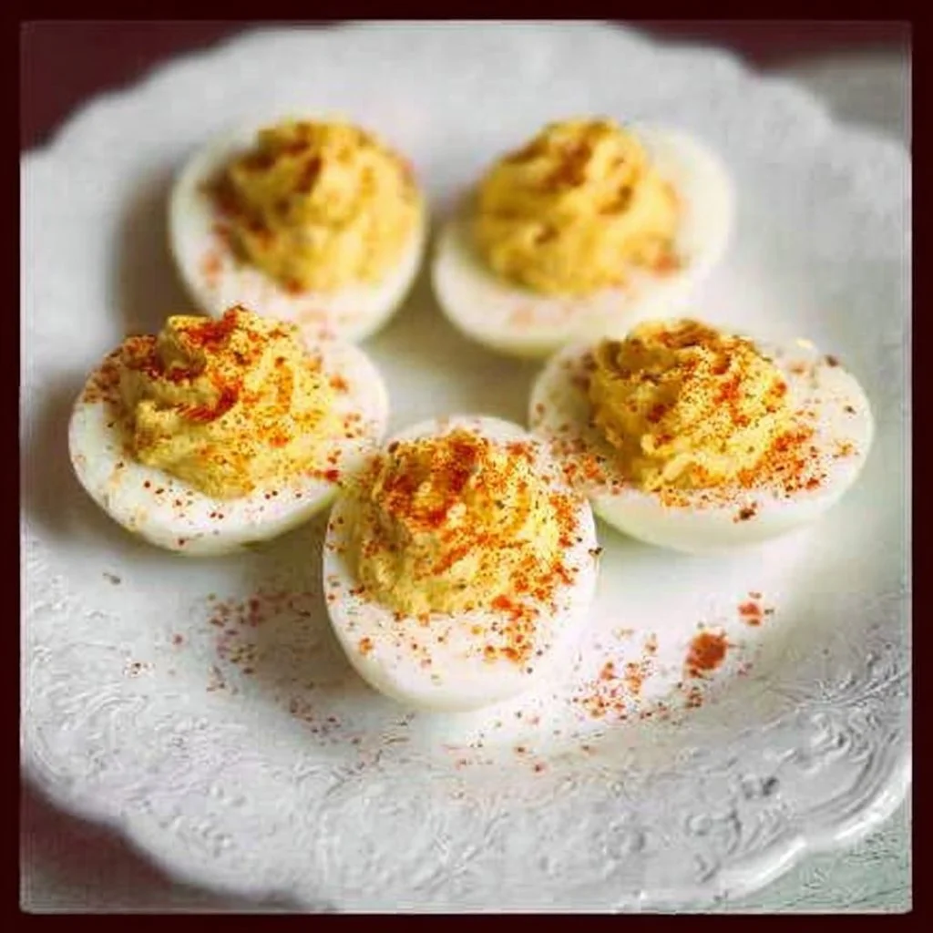 Plate of classic deviled eggs garnished with paprika and herbs